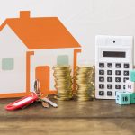 house-key-stacked-coins-calculator-and-math-blocks-on-wooden-table